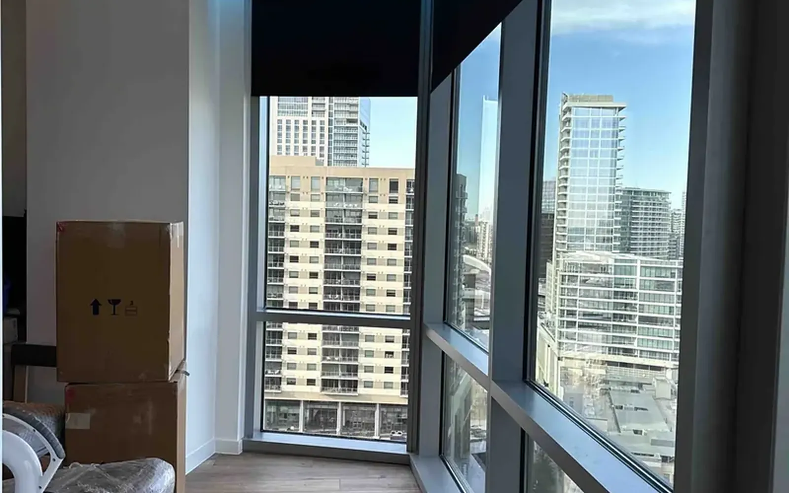 High-rise living room window with motorized shades and the Dallas skyline behind