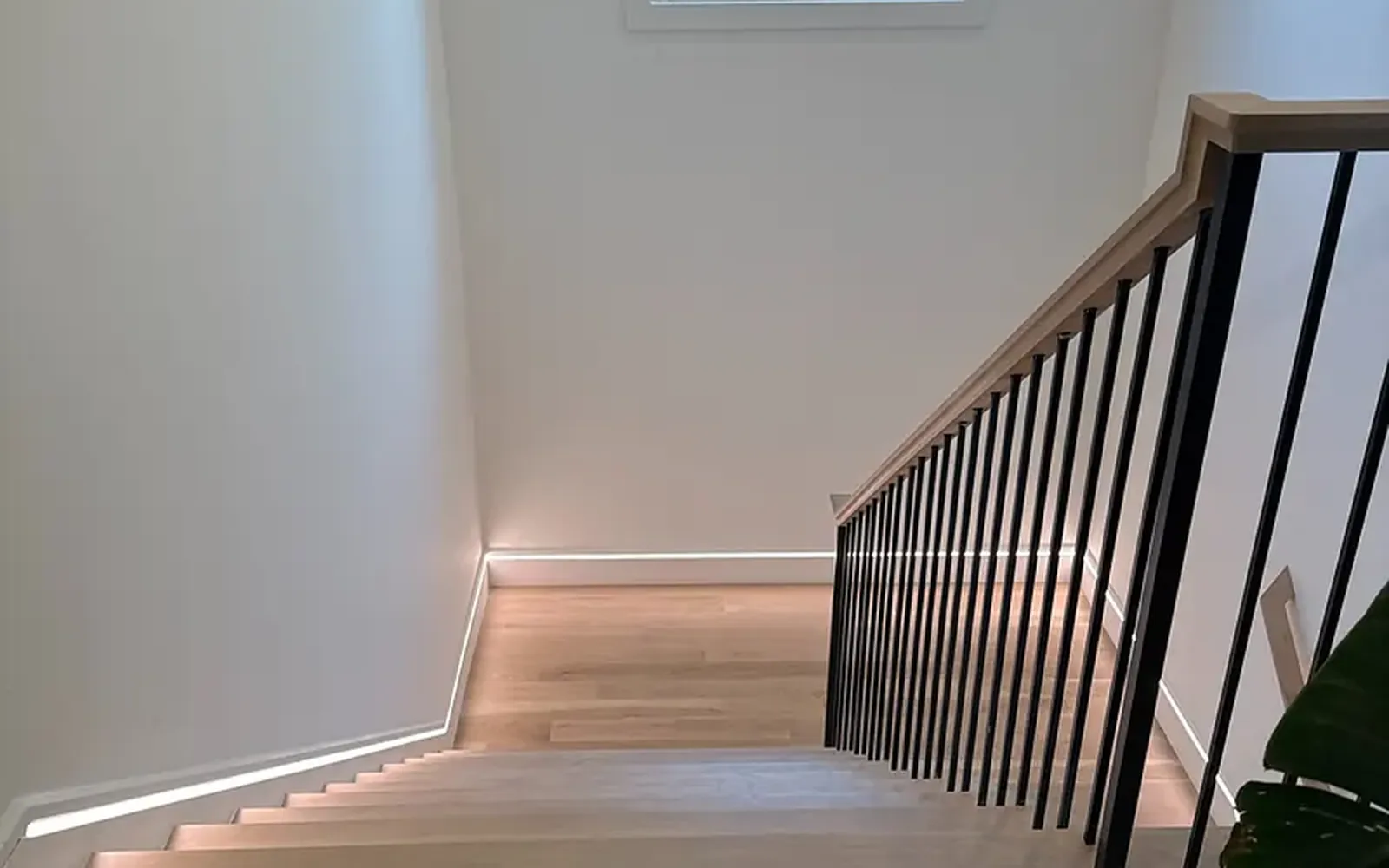 Staircase with a recessed line of LED strip lighting running along the wall beside the treads