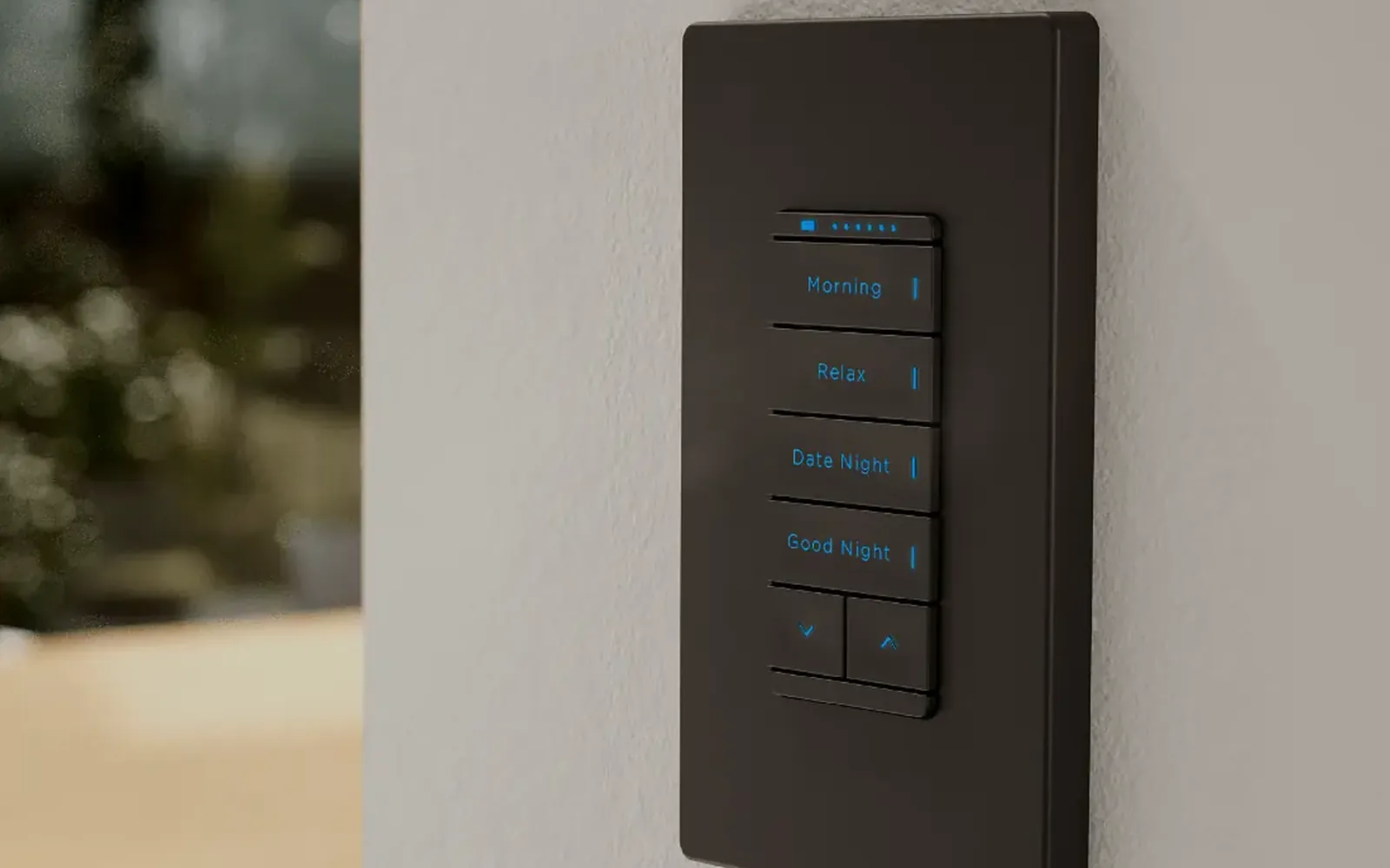 Engraved lighting keypad in a dark finish mounted on a wall, with buttons labeled for scenes