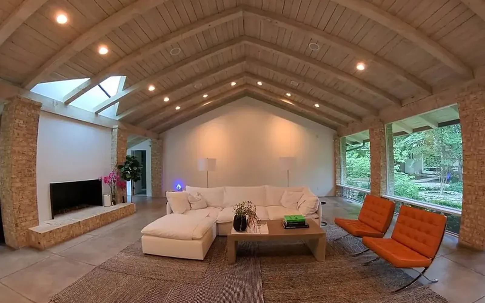 Vaulted living room with warm cove lighting along the ceiling and two orange armchairs, from a WH Technologies lighting project
