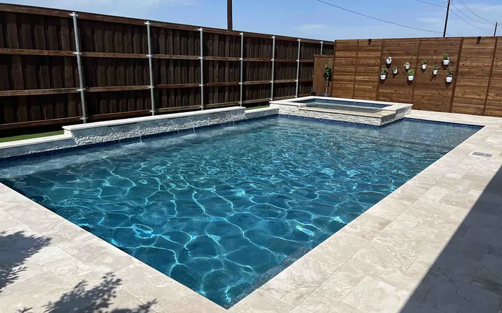 Backyard pool on a WH Technologies project with small bullet speakers mounted low along the fence line, aimed inward across the water