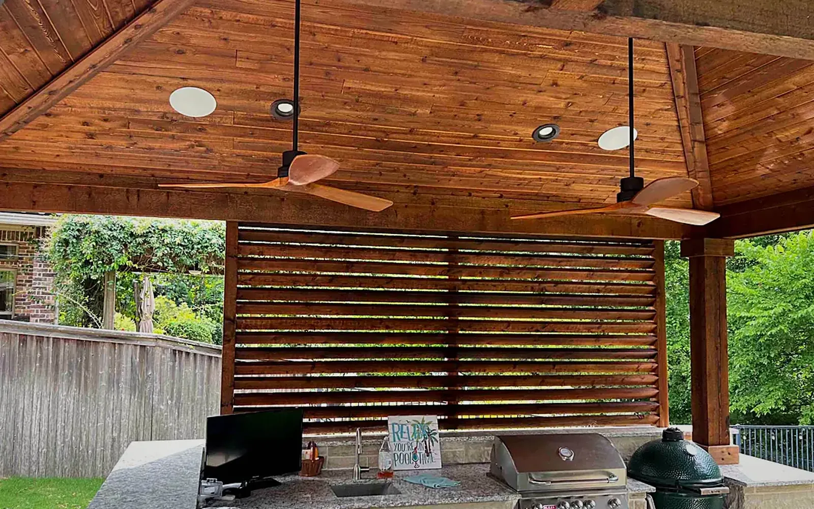 Covered patio bar with a stained wood ceiling and two round flush-mount ceiling speakers above the counter