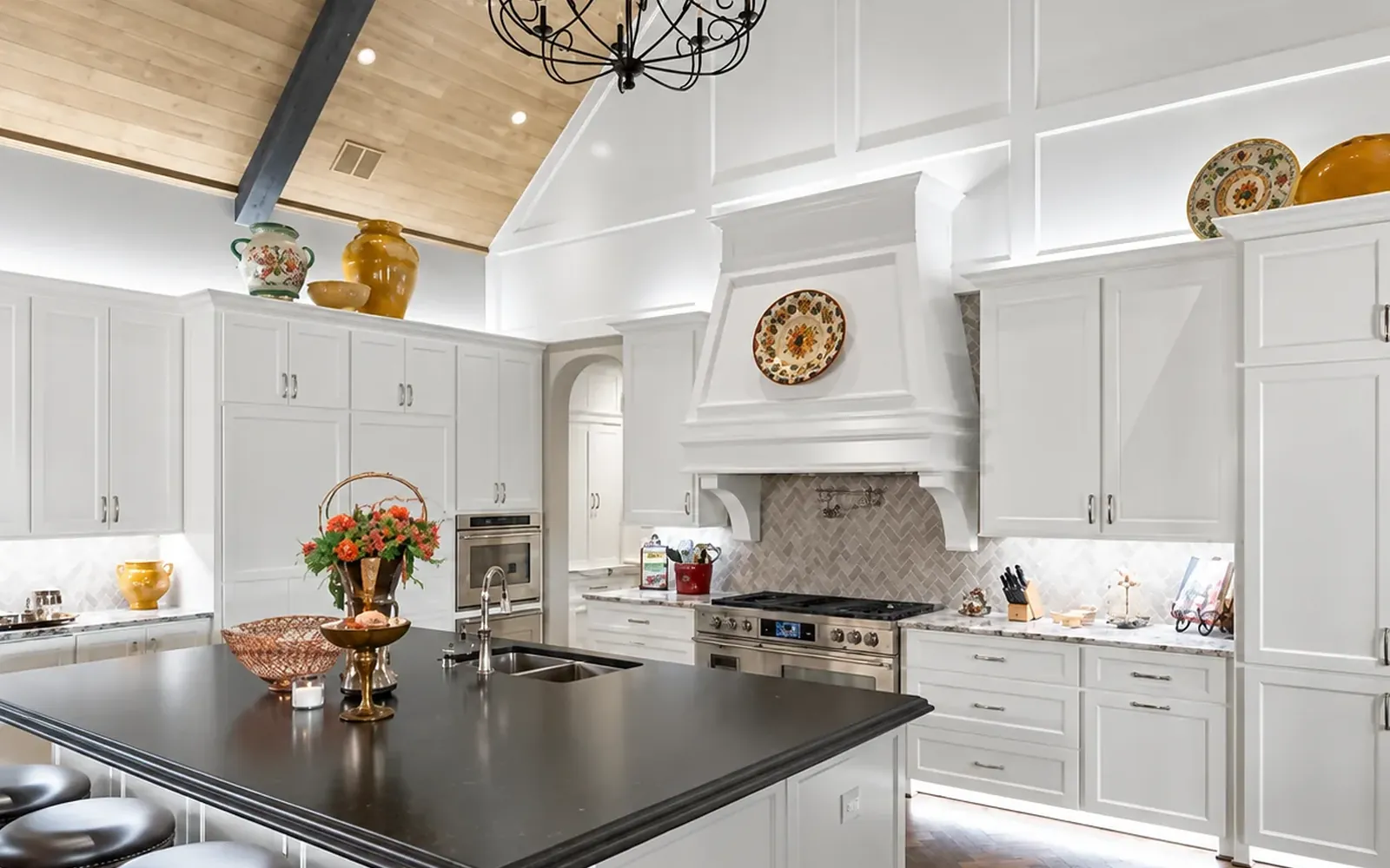 White kitchen after a WH Technologies lighting project, with under-cabinet task light, pendants over the island and lit glass-front cabinets