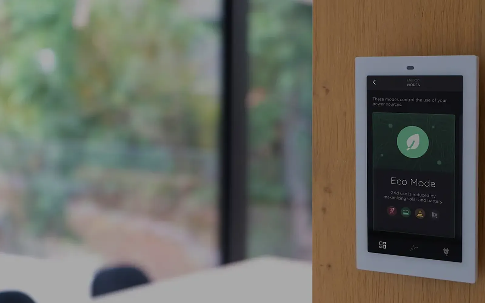 Savant touch panel mounted on a wall beside a window, with trees visible outside