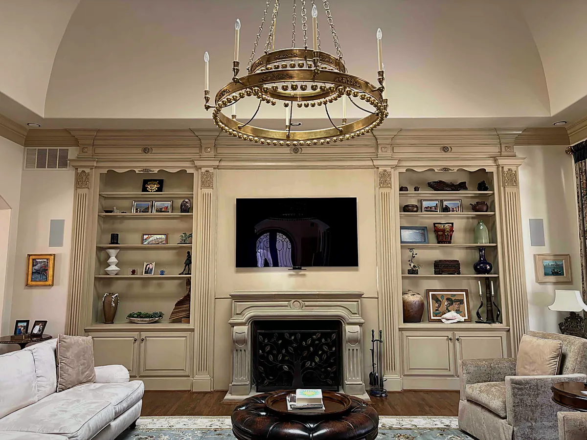 Living room with a concealed display over the mantel and lit shelving, WH Technologies