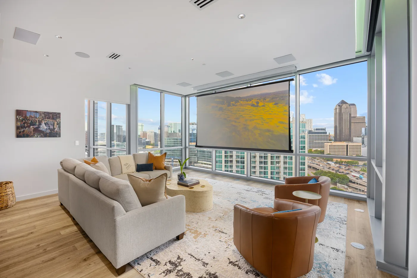 Living room with the projection screen lowered in front of the windows and the Dallas skyline behind it