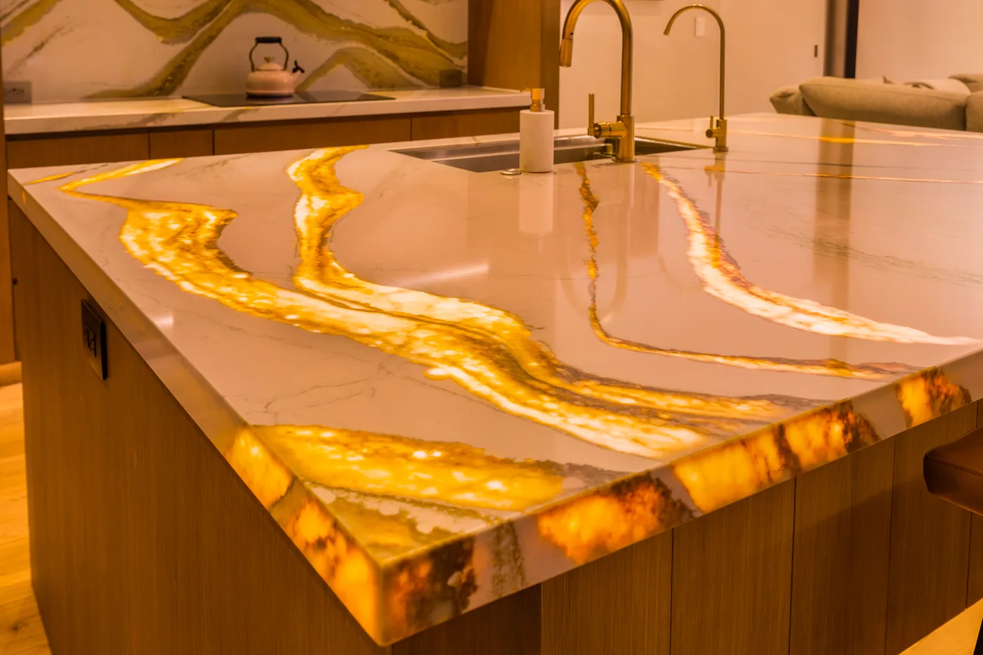 Backlit onyx kitchen island glowing amber in the evening, brass fixtures and walnut cabinetry