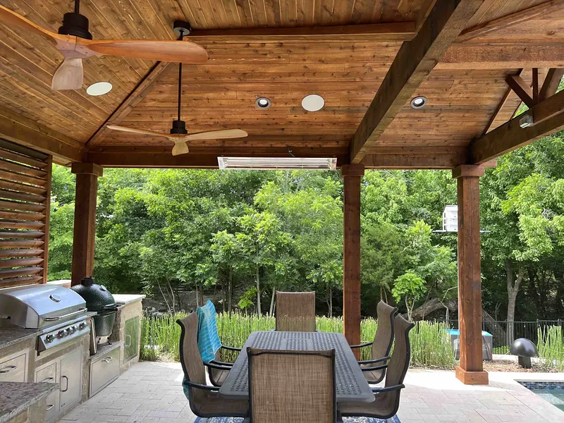 Covered patio with a wood ceiling, fans, in-ceiling speakers and an outdoor kitchen