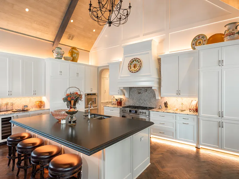 White kitchen with under-cabinet and in-cabinet lighting and a dark island
