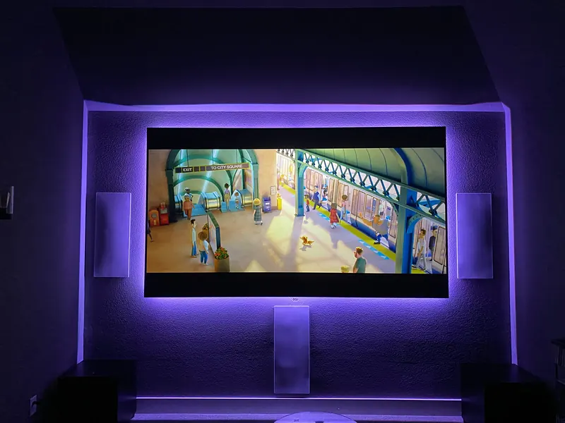 Media room with a large screen and purple bias lighting behind it