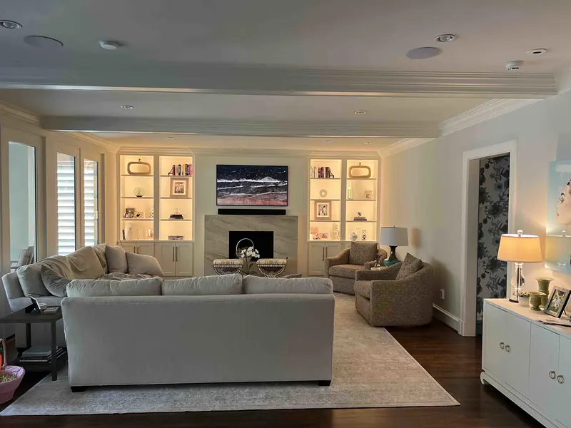 Living room with lit built-in shelves and a frame TV above the fireplace