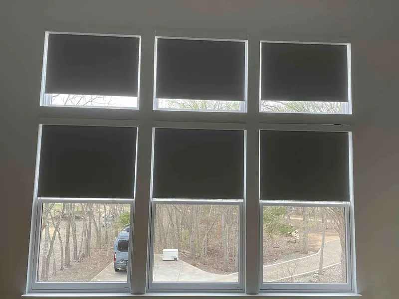 Grid of windows with motorized roller shades lowered halfway