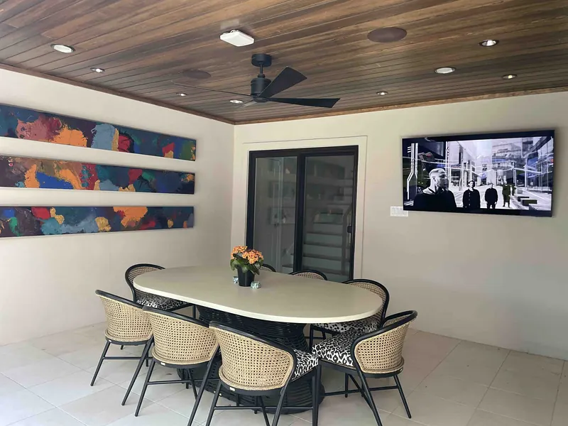 Covered patio dining area with a wood ceiling, fans and a wall-mounted outdoor TV