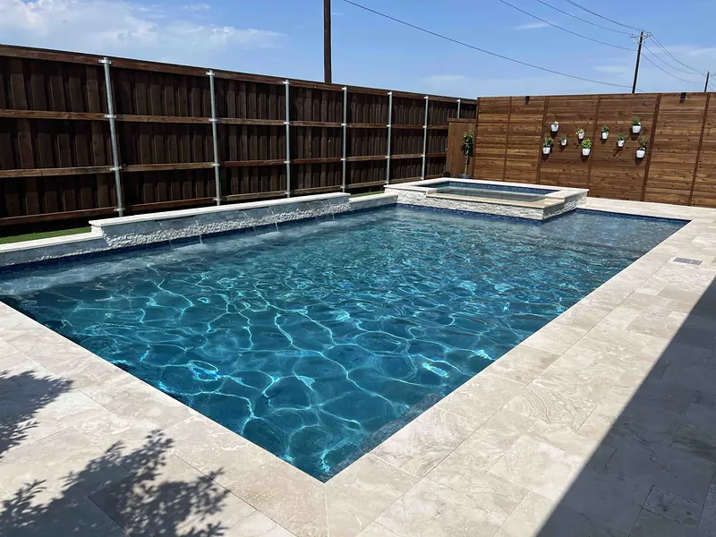 Backyard pool with a spa and bullet speakers mounted on the fence