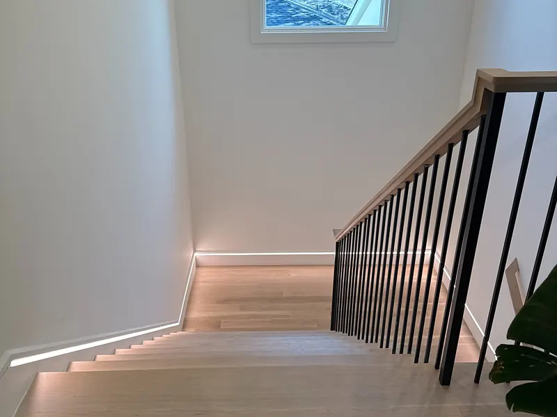 Oak staircase with a black railing and a continuous LED light line along the steps