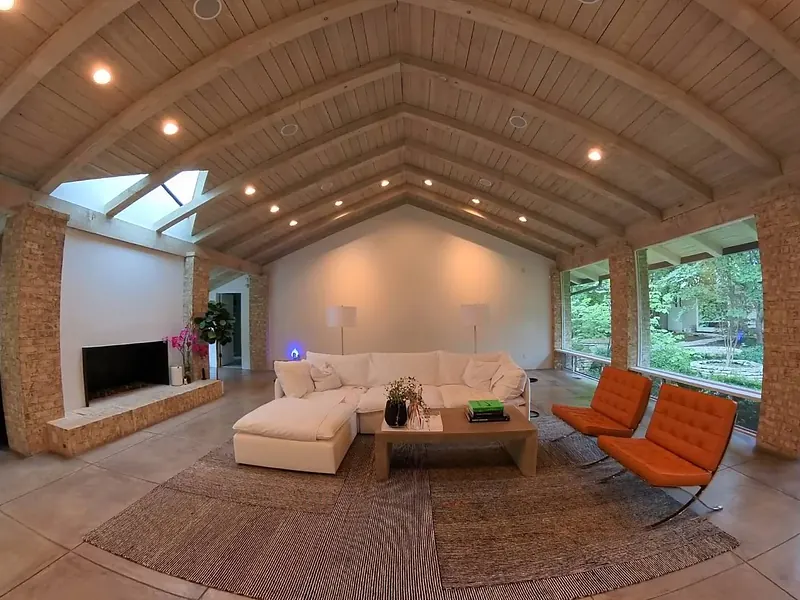 Living room with a vaulted wood ceiling, recessed lighting and a wall-mounted TV over the fireplace