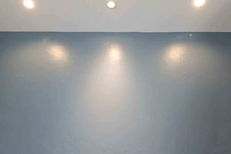 Blue accent wall washed by three recessed downlights