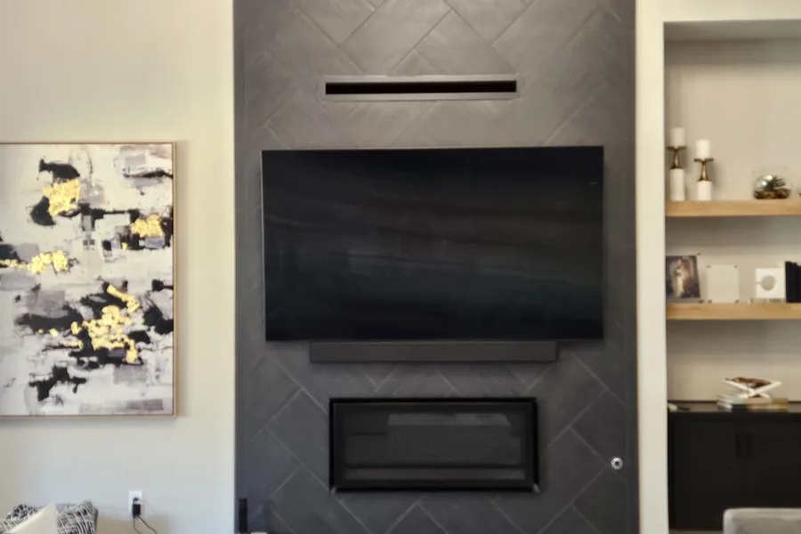 Dark tiled fireplace wall with a mounted TV and a soundbar, open shelves either side