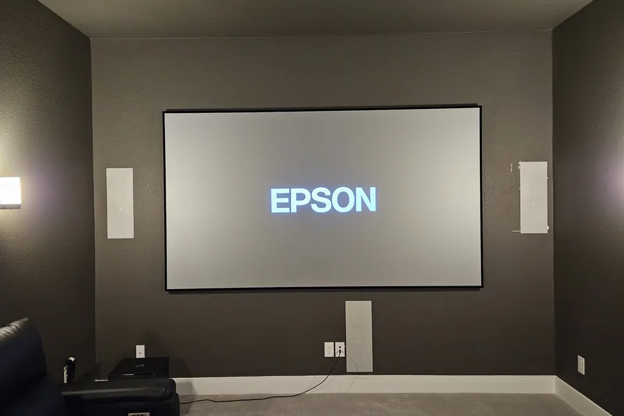 Media room with a projection screen, in-wall speakers and dark walls