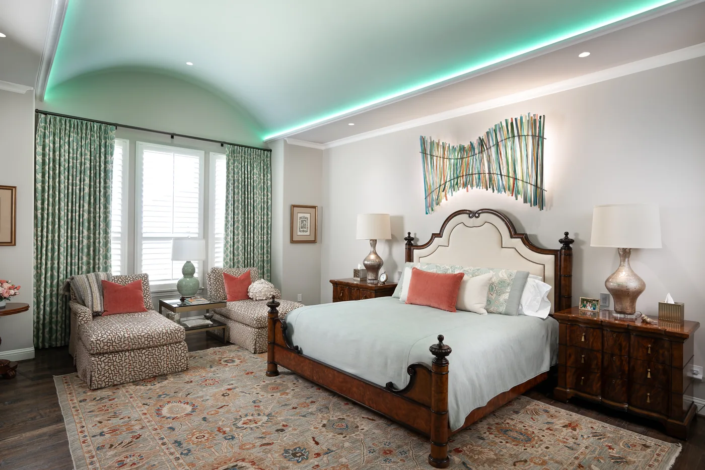 Primary bedroom with a soft teal cove light along the ceiling and warm bedside lamps