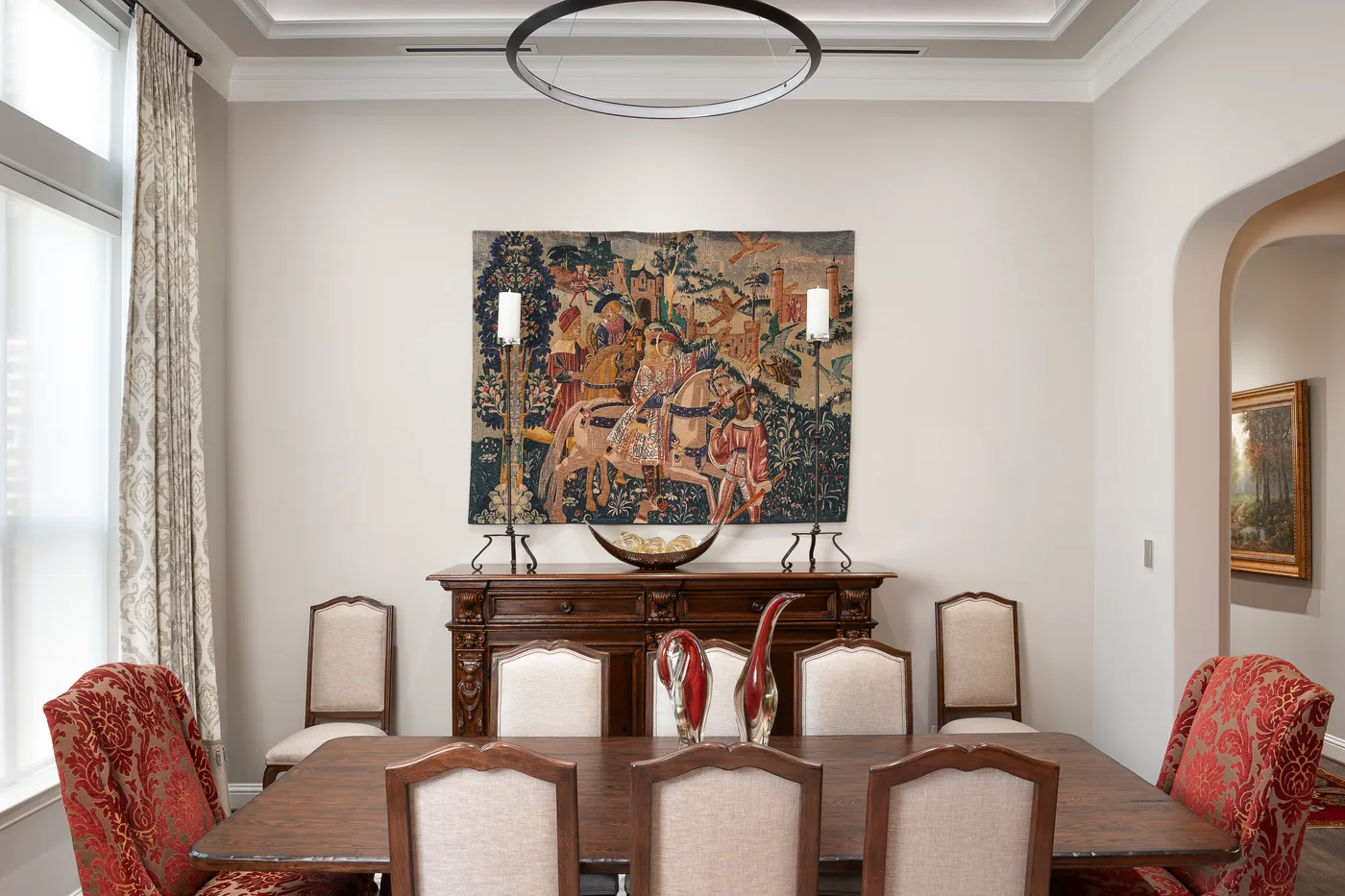 Dining room with a warm cove light in the tray ceiling, a chandelier and an upholstered table