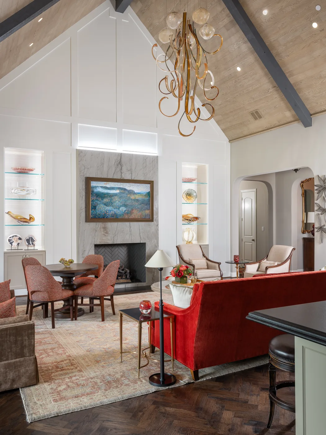 Living room seen past a red sofa toward the lit display niches and the fireplace