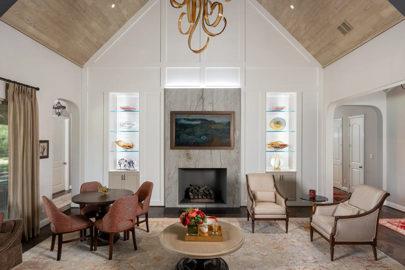 Wide view of the living room with a vaulted wood ceiling, chandelier and lit niches