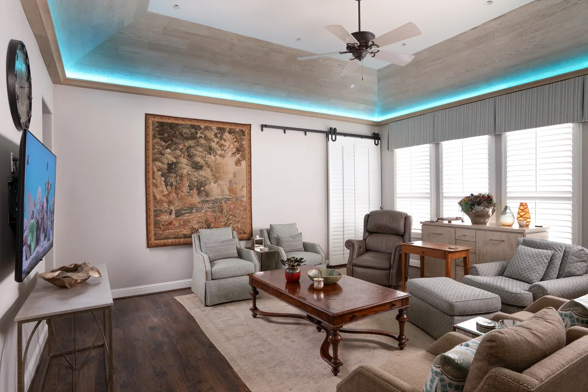 Den after: an orange cove light along the tray ceiling, tapestry and TV