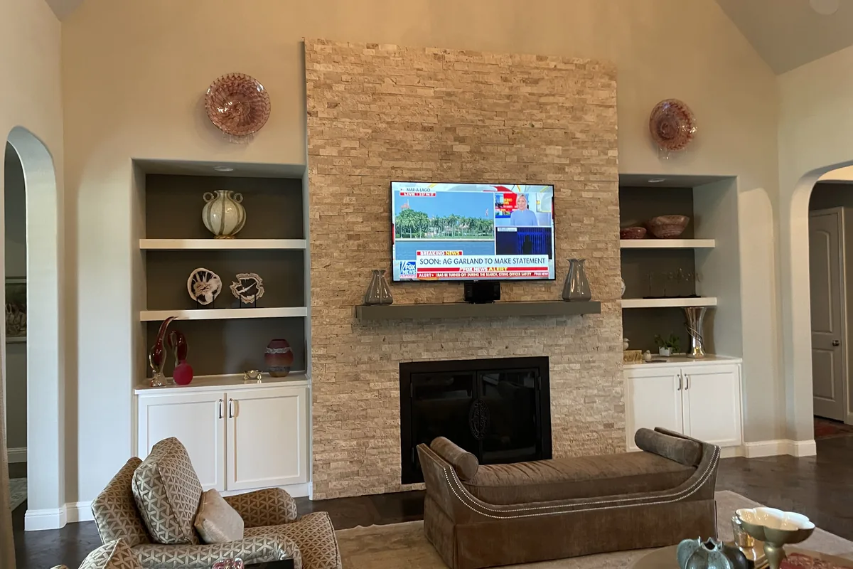 Living room before: brick fireplace with a TV above and white built-ins