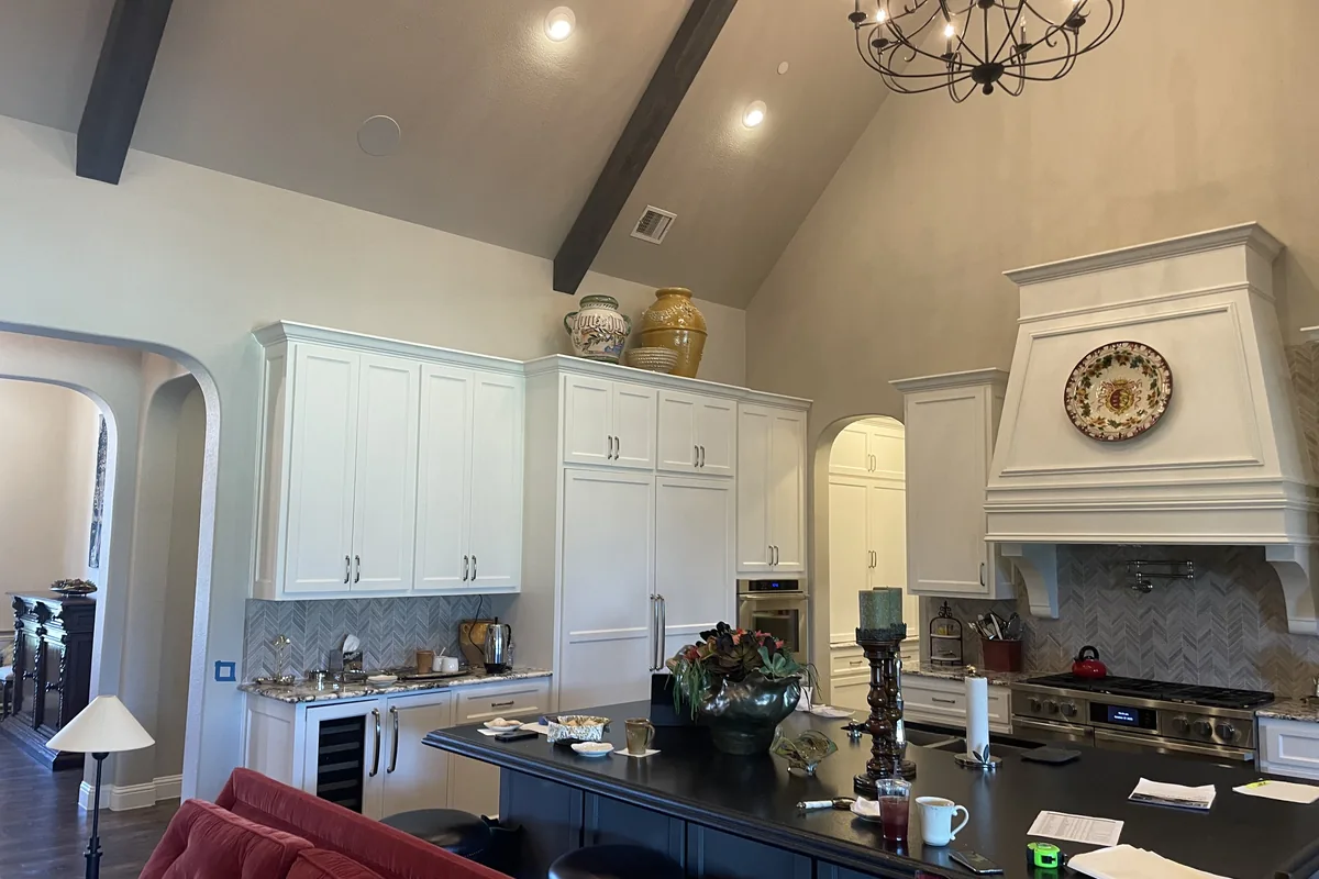Kitchen before: white cabinets, dark island and a single chandelier