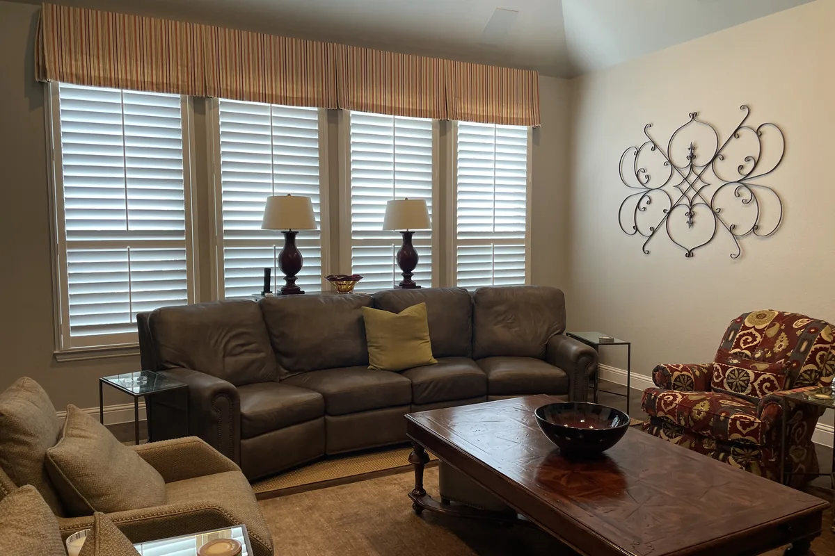 Den before: sofas under a window with shutters and a ceiling fan