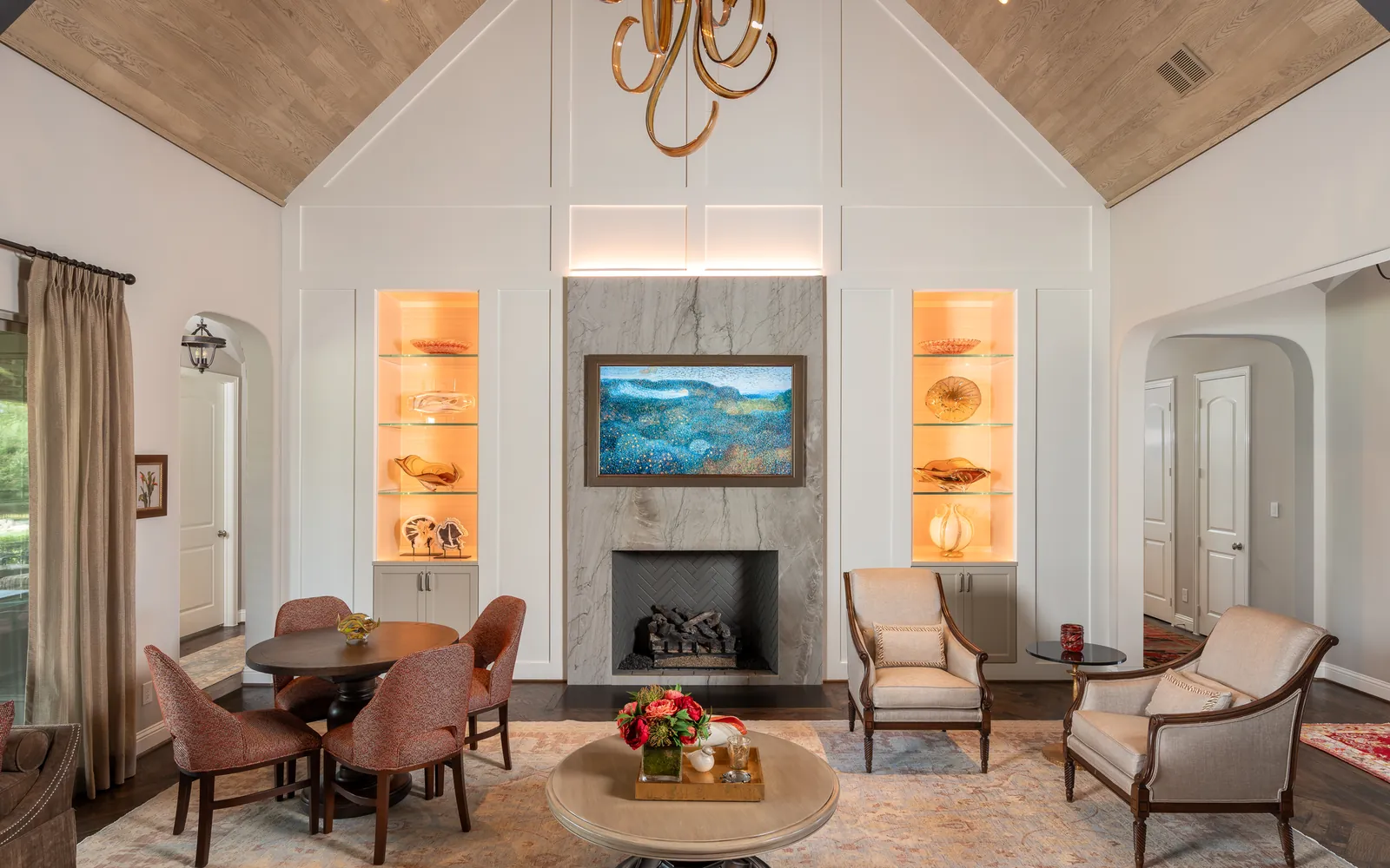 Living room with a vaulted wood ceiling, a marble fireplace, a TV above it and two lit display niches