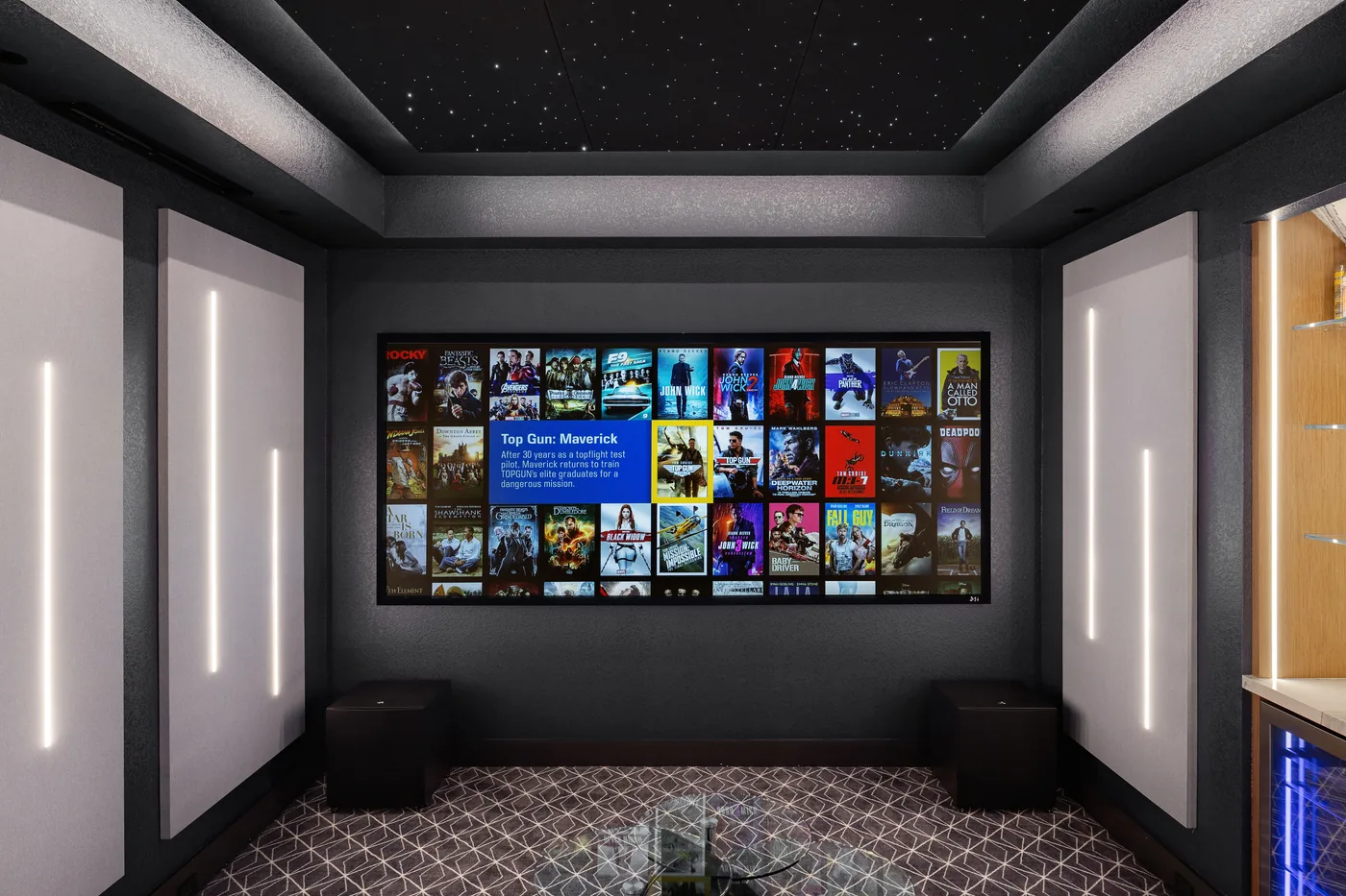 Theater with the movie library on screen, white acoustic panels lit by vertical LED strips and two rows of recliners