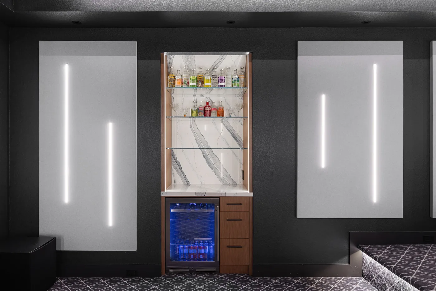 Backlit marble bar niche with a glass-front fridge between acoustic panels