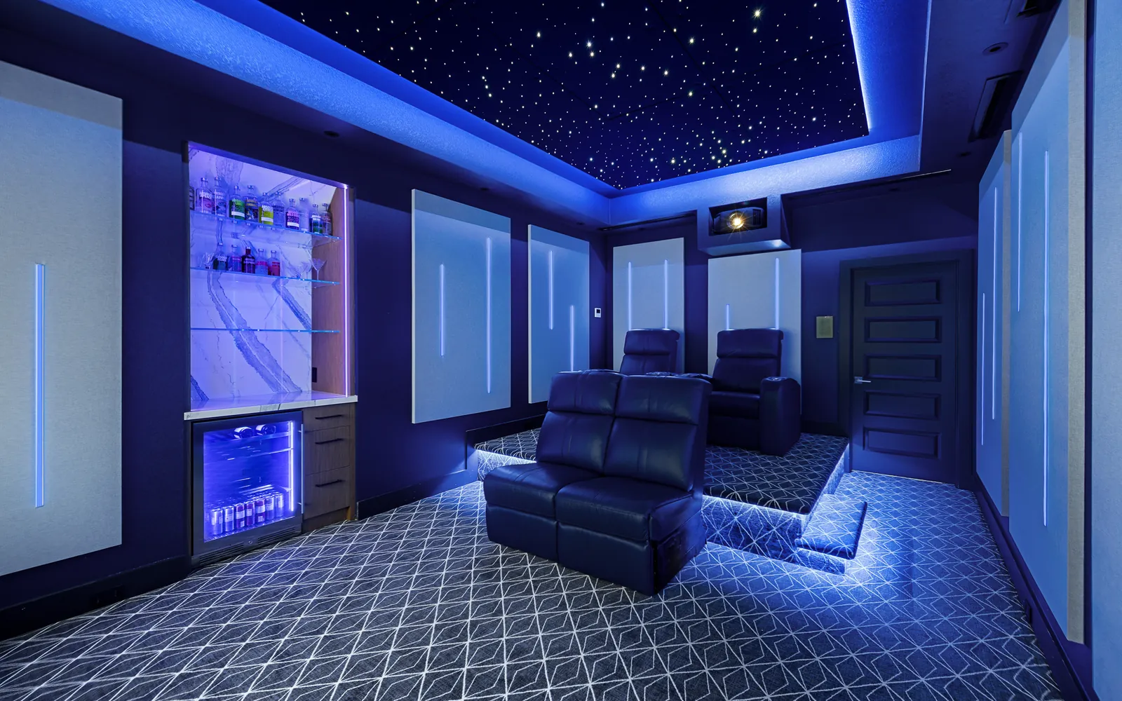 Dedicated home theater in a blue lighting scene with a fiber-optic star ceiling, lit acoustic panels and leather recliners