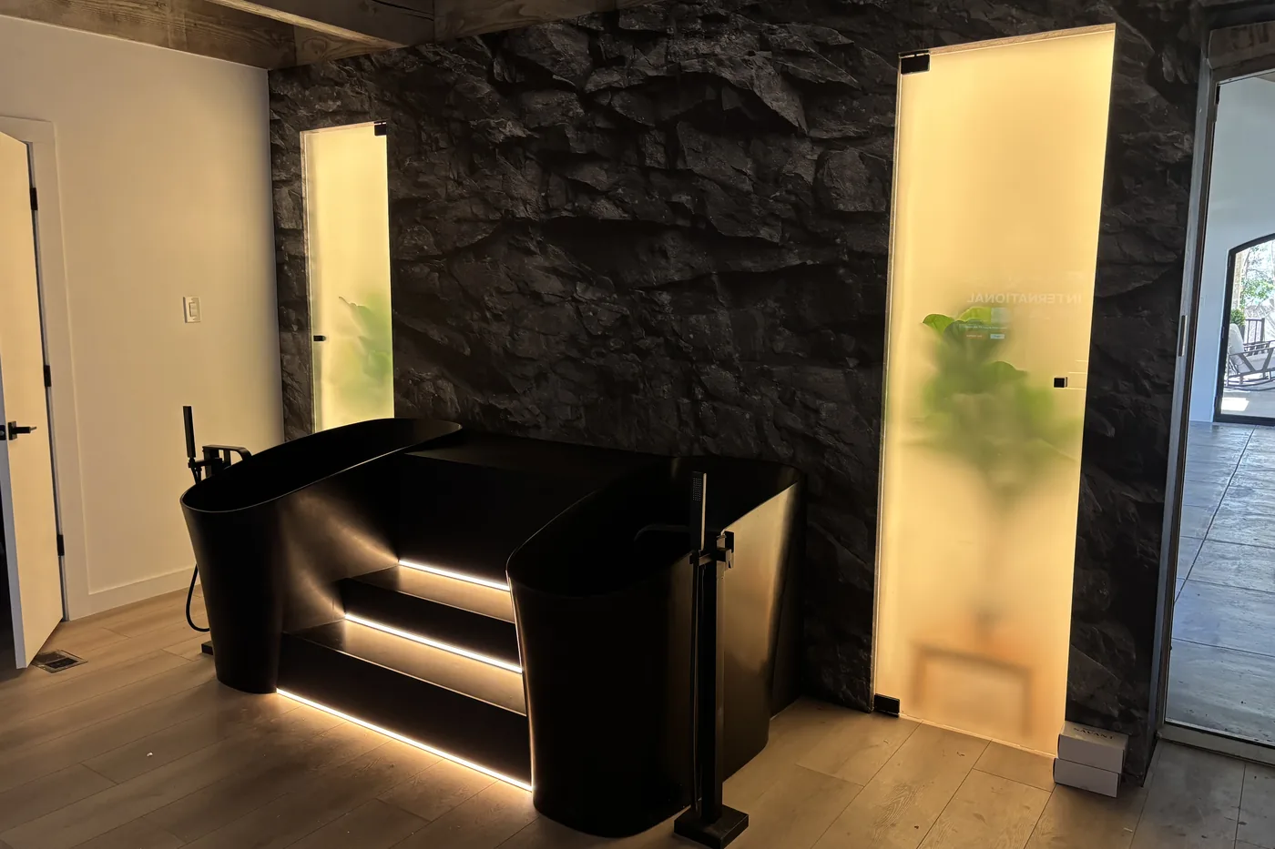 Backlit frosted panels and a lit step detail against a dark stone wall in the gym