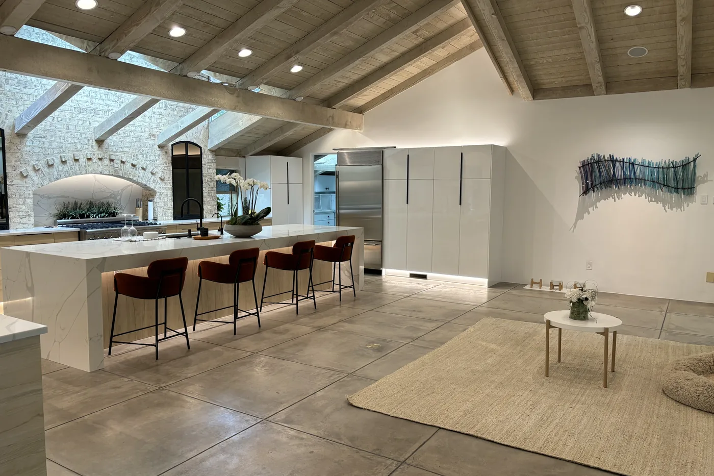 Mid-century kitchen with a stone arch, vaulted wood ceiling, long island and warm downlights