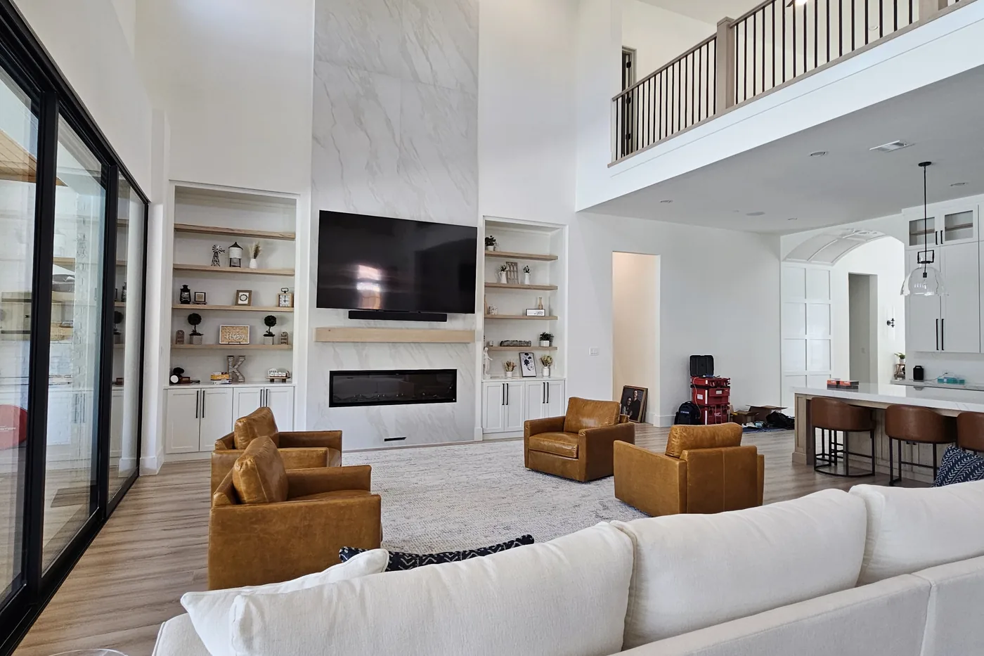 Two-story great room with a stone fireplace, a TV above it and a long white sofa