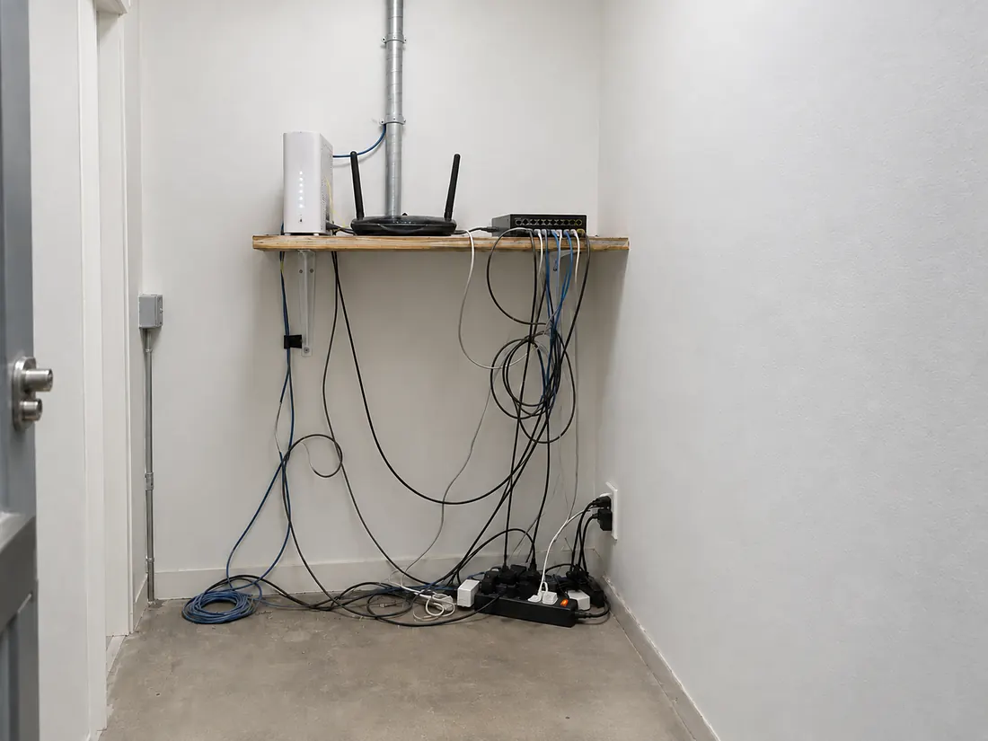 The same network closet with an ISP router and loose cables on a shelf, and with a labelled, ventilated equipment rack installed by WH Technologies